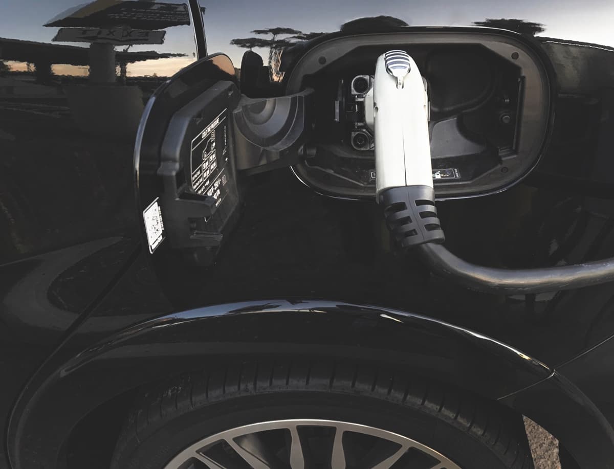 Câble de recharge branché sur une voiture noire.
