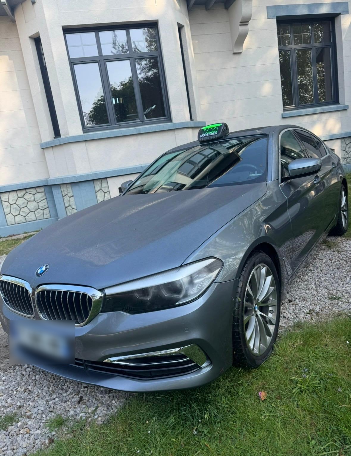 Taxi BMW gris devant un bâtiment.